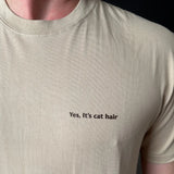 Beige t-shirt with 'Yes, it's cat hair' text on a plain background