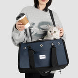 Person holding a coffee cup and a cat in a blue pet carrier against a white background